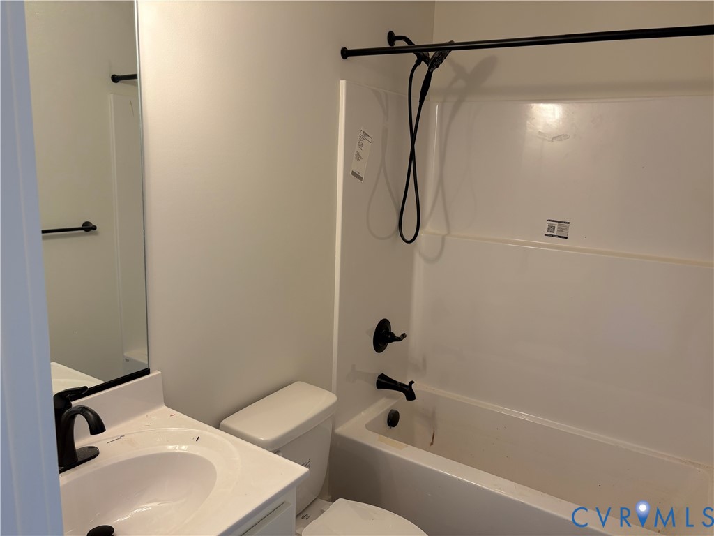 Bathroom featuring a white vanity with a rectangular basin, matte black fixtures, a wall-mounted mirror, and a tub-shower combination with a matte black shower rod