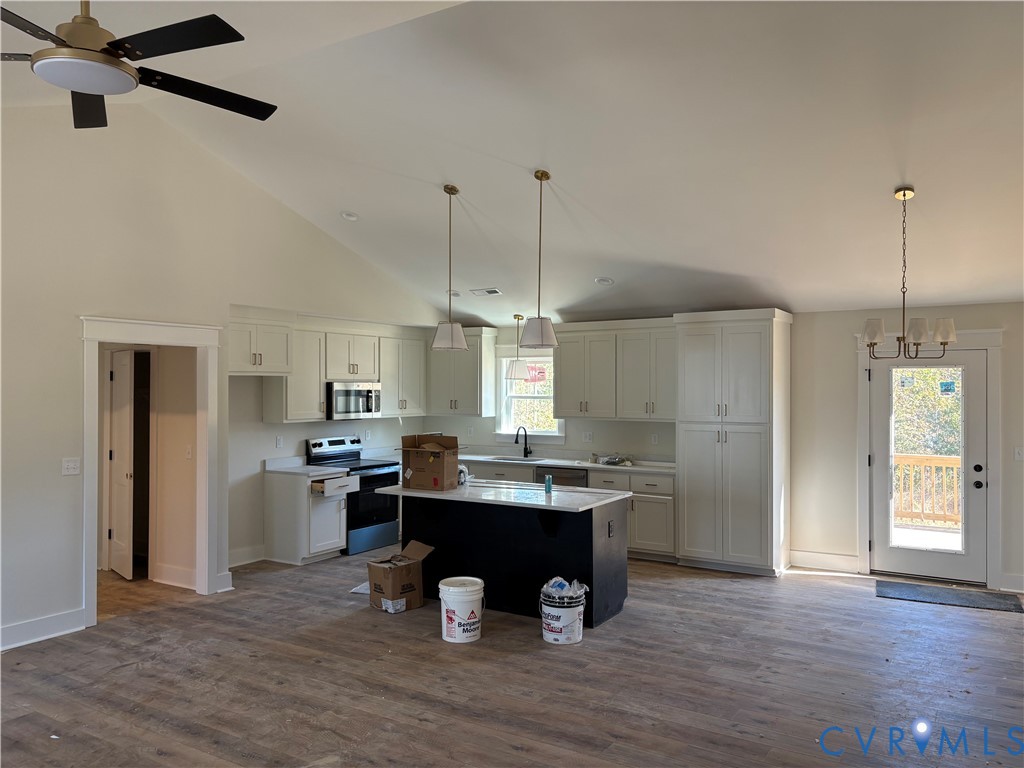 Kitchen featuring vaulted ceilings, wood-finish flooring, a central island with a contrasting base, shaker-style cabinetry, and multi-pendant lighting Kitchen featuring vaulted ceilings, wood-finish flooring, a central island with a contrasting base, shaker-style cabinetry, and multi-pendant lighting