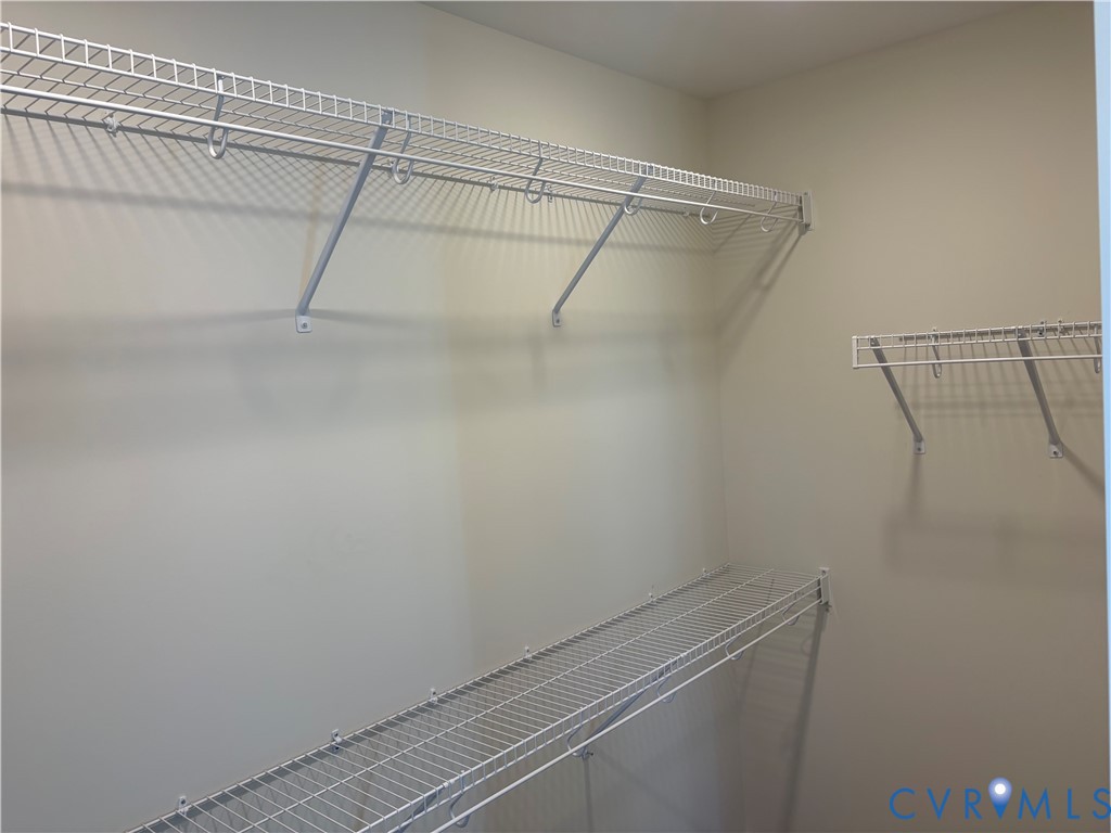 Walk-in closet featuring multi-level white wire shelving and integrated garment rods Walk-in closet featuring multi-level white wire shelving and integrated garment rods