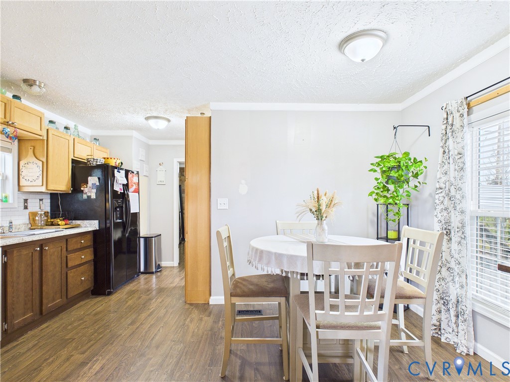 Kitchen featuring light-tone upper cabinetry, dark-tone lower cabinetry, wood-finish flooring, and a window with horizontal blinds