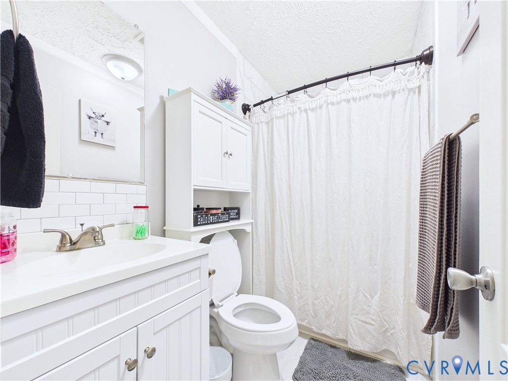 White vanity featuring a beadboard facade, rectangular basin, dual-handle faucet, and white subway tile backsplash, complemented by an integrated over-the-toilet storage cabinet