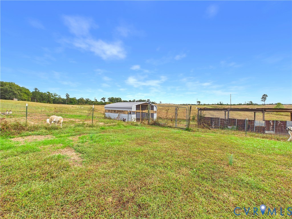 Expansive pasture featuring fenced enclosures and metal-roofed storage structures