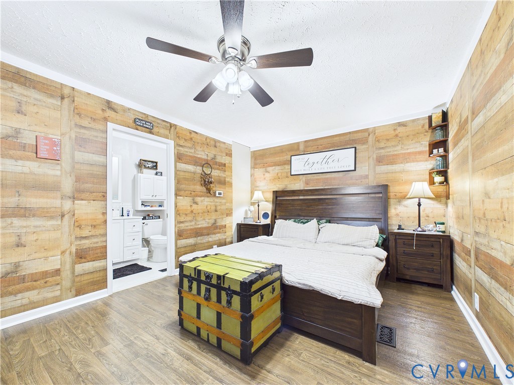 Interior space featuring horizontal wood-plank wall treatments, wood-finish flooring, a ceiling fan with integrated lighting, and corner-mounted built-in shelving