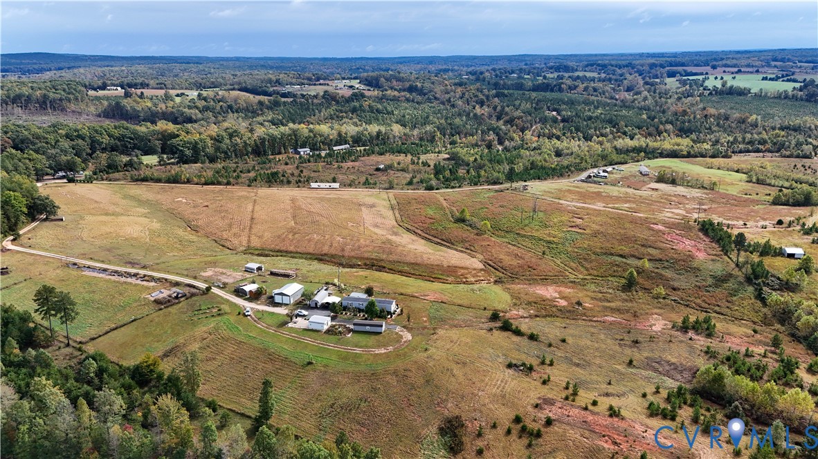 Expansive acreage featuring rolling open fields, multiple auxiliary structures, and perimeter woodland