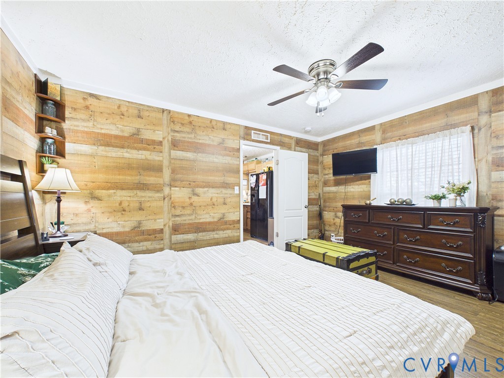 Horizontal wood-paneled walls, built-in corner shelving, and a ceiling fan with integrated lighting