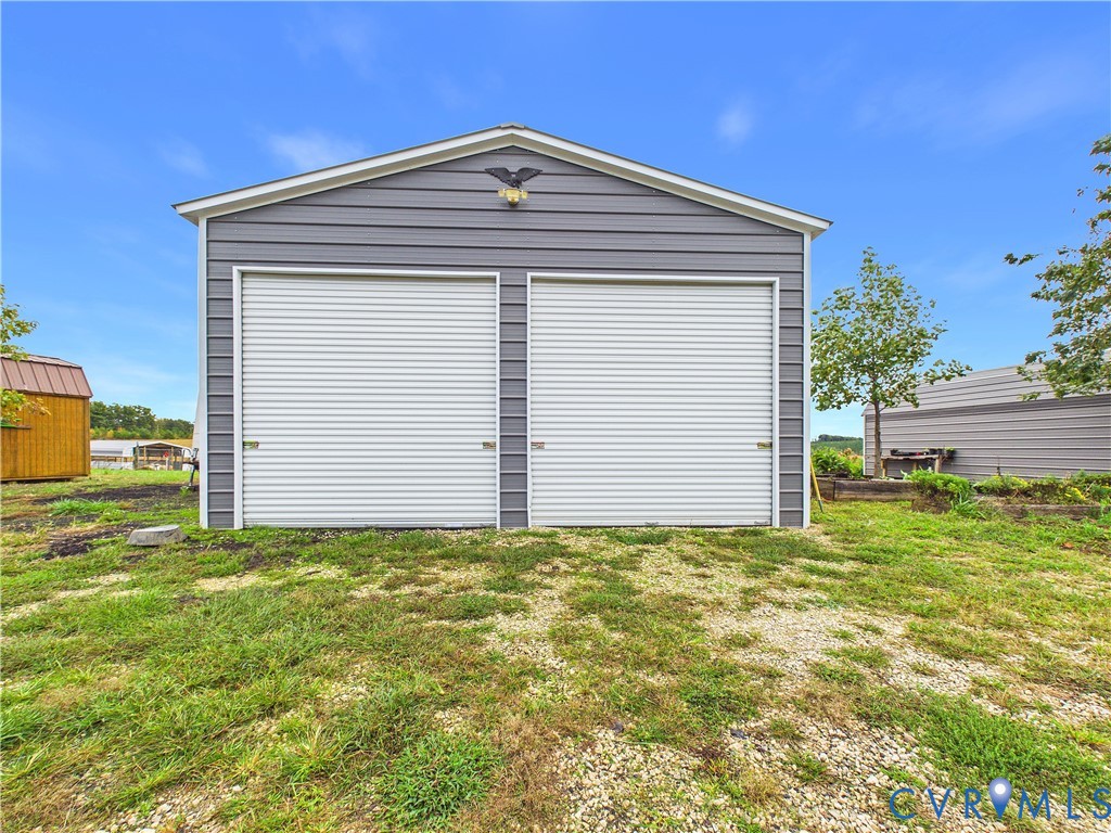 Detached two-car garage with grey horizontal siding, dual roll-up doors, and an exterior mounted light fixture