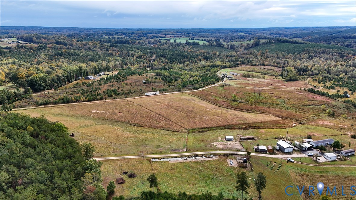 Expansive acreage featuring cleared pasture land, dense mature timber, and multiple outbuildings