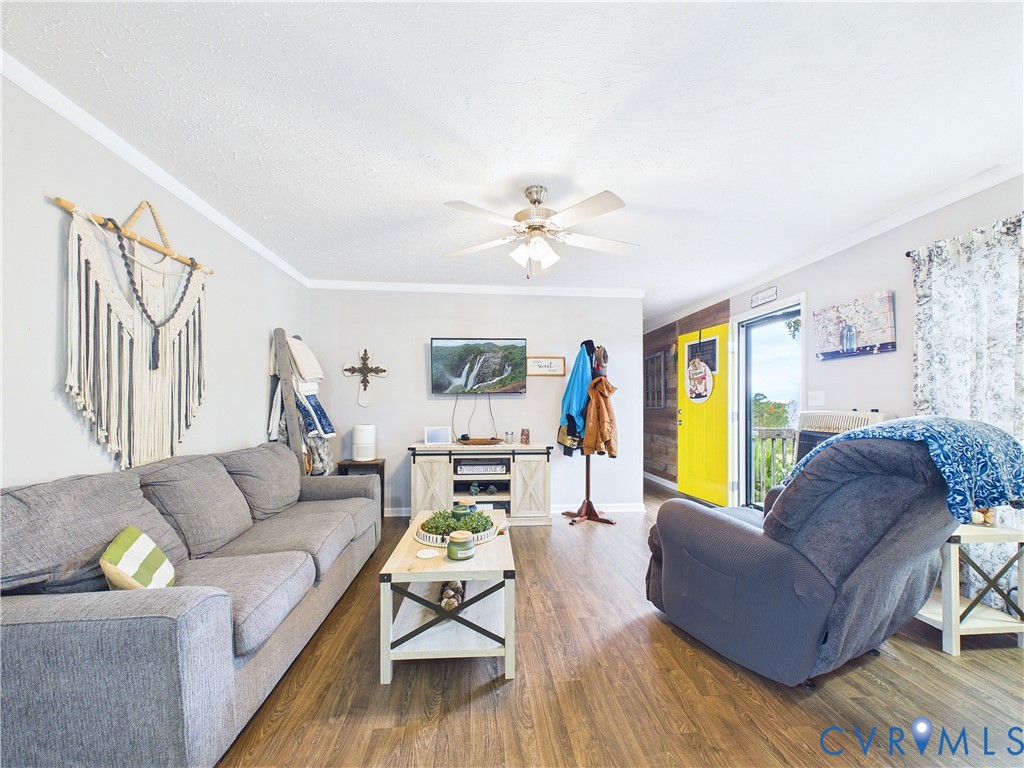 Wood-finish flooring, ceiling fan with integrated lighting, textured walls, and wood-paneled accent wall Wood-finish flooring, ceiling fan with integrated lighting, textured walls, and wood-paneled accent wall
