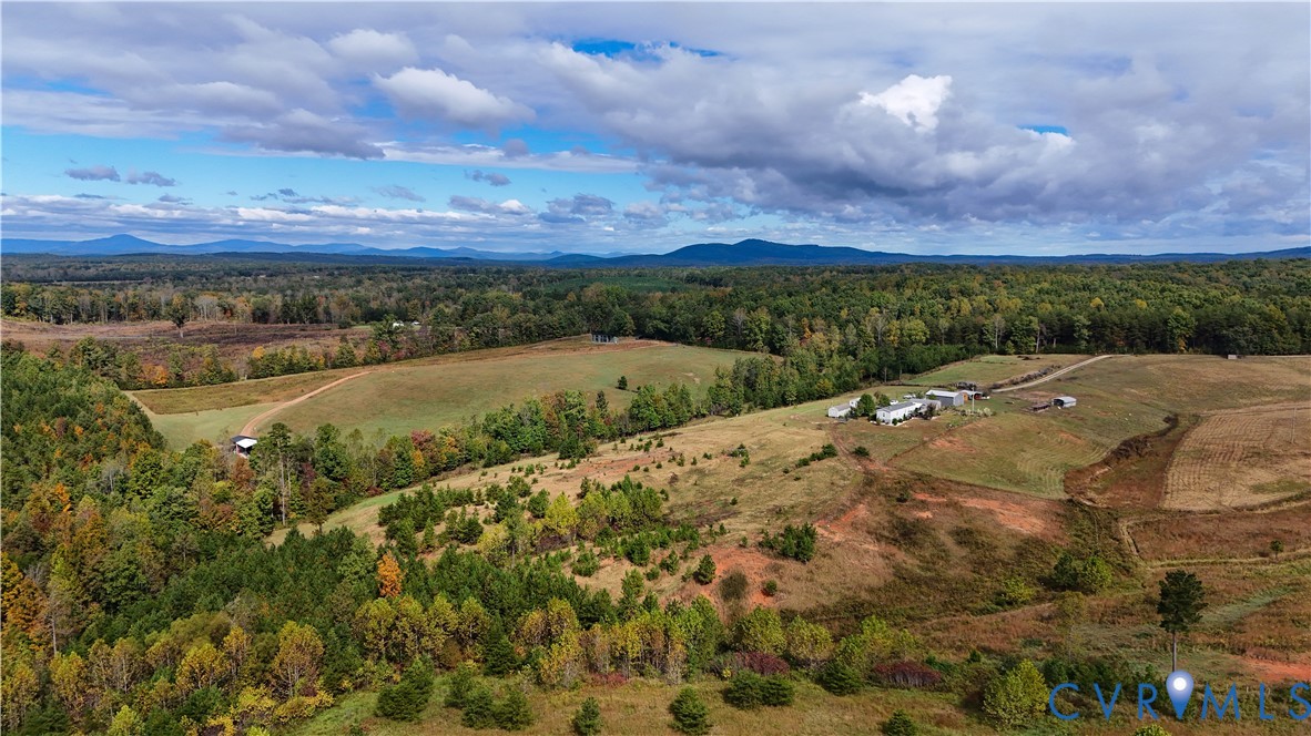 Expansive acreage featuring rolling topography, mature forest coverage, cleared open fields, and mountain range scenery