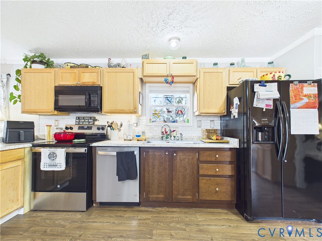 Kitchen featuring natural wood cabinetry, stone-finish countertops, subway tile backsplash, and wood-finish flooring