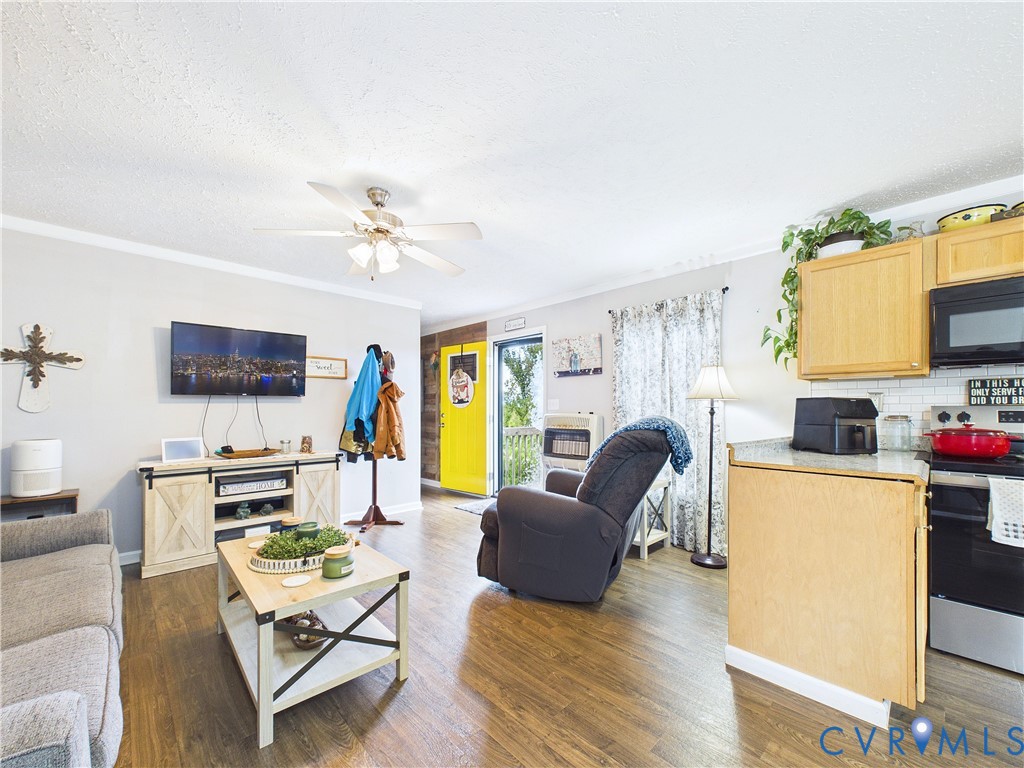 Open-concept area featuring wood-finish flooring, ceiling fan, natural wood cabinetry, and a white tile backsplash