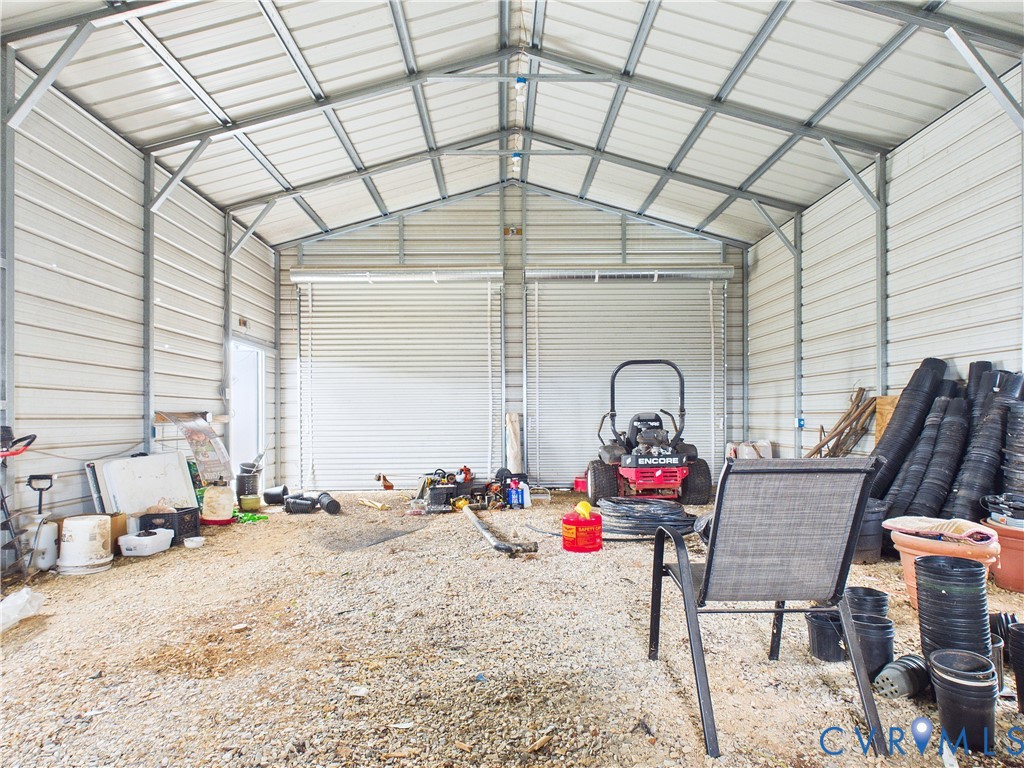 Detached metal storage structure featuring a vaulted ceiling, exposed steel framing, and dual roll-up garage doors