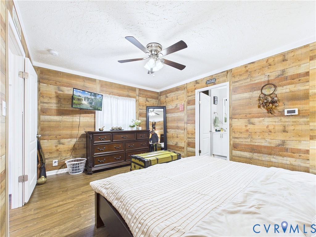 Horizontal wood-plank wall paneling, wood-finish flooring, and a ceiling fan with integrated lighting