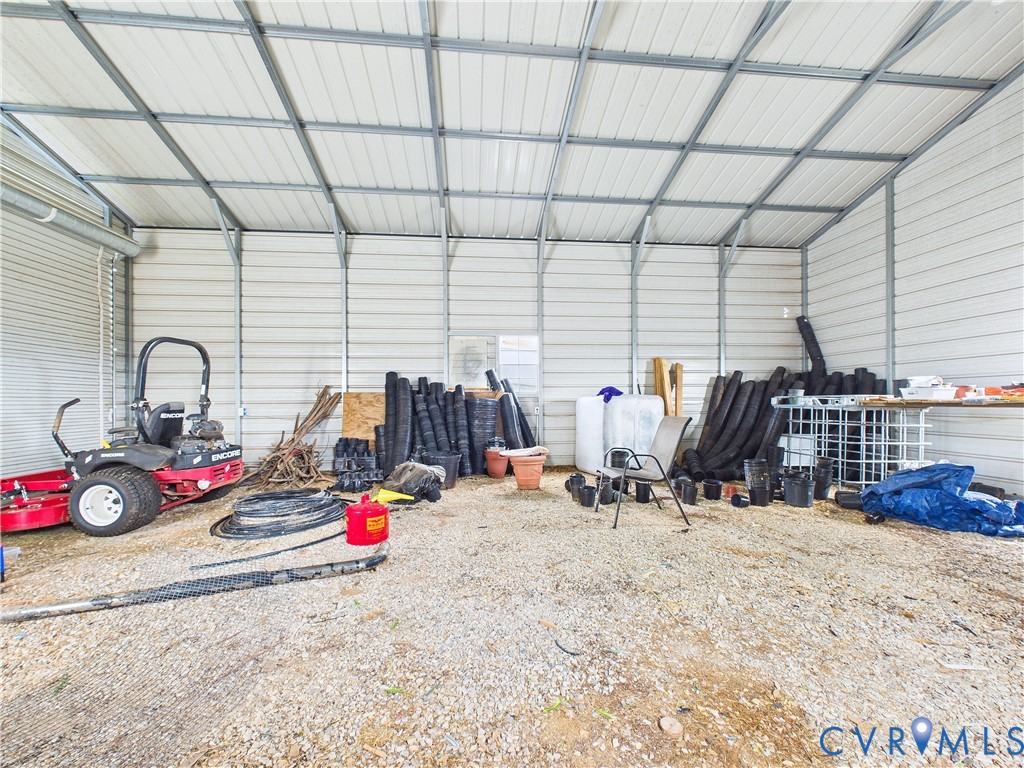 Detached metal-frame storage structure featuring corrugated metal wall panels, exposed steel truss ceiling, and gravel flooring