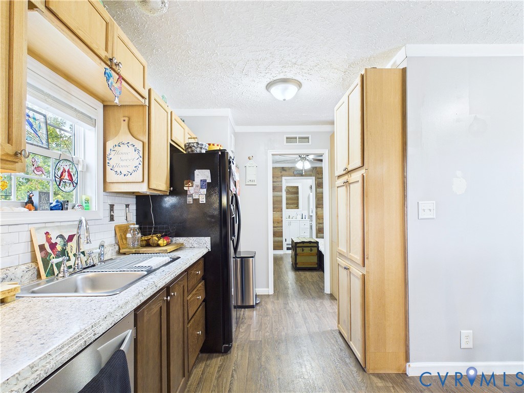 Kitchen featuring wood-finish cabinetry, stone-patterned countertops, a white subway tile backsplash, a dual-basin stainless steel sink with a chrome gooseneck faucet, and wood-finish flooring