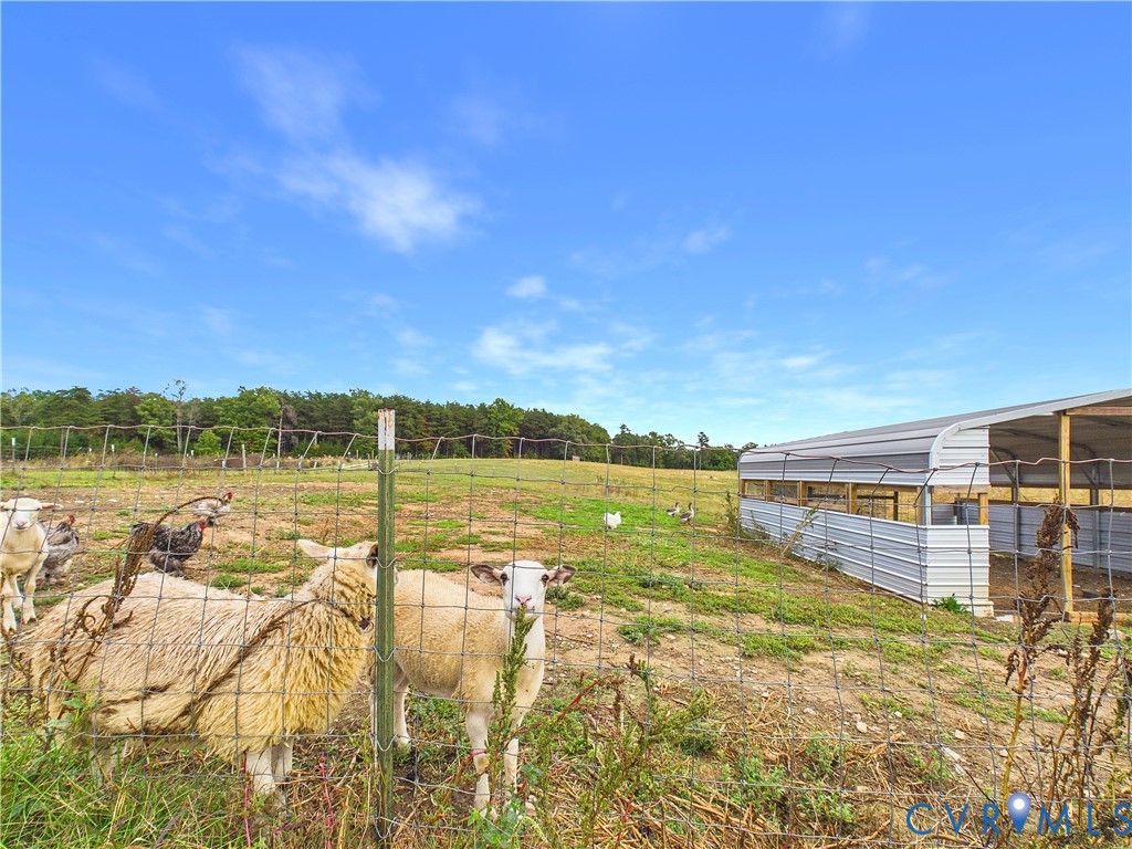 Expansive open pasture featuring perimeter wire fencing and a metal-clad agricultural structure