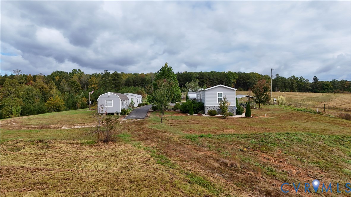 Expansive acreage featuring a paved driveway, detached storage structure, and stone-finish foundation detailing