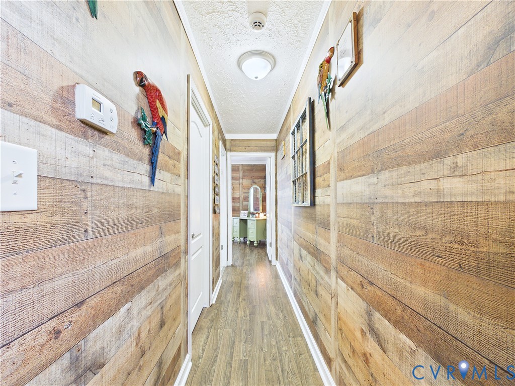 Hallway featuring horizontal wood-plank wall paneling and wood-finish flooring