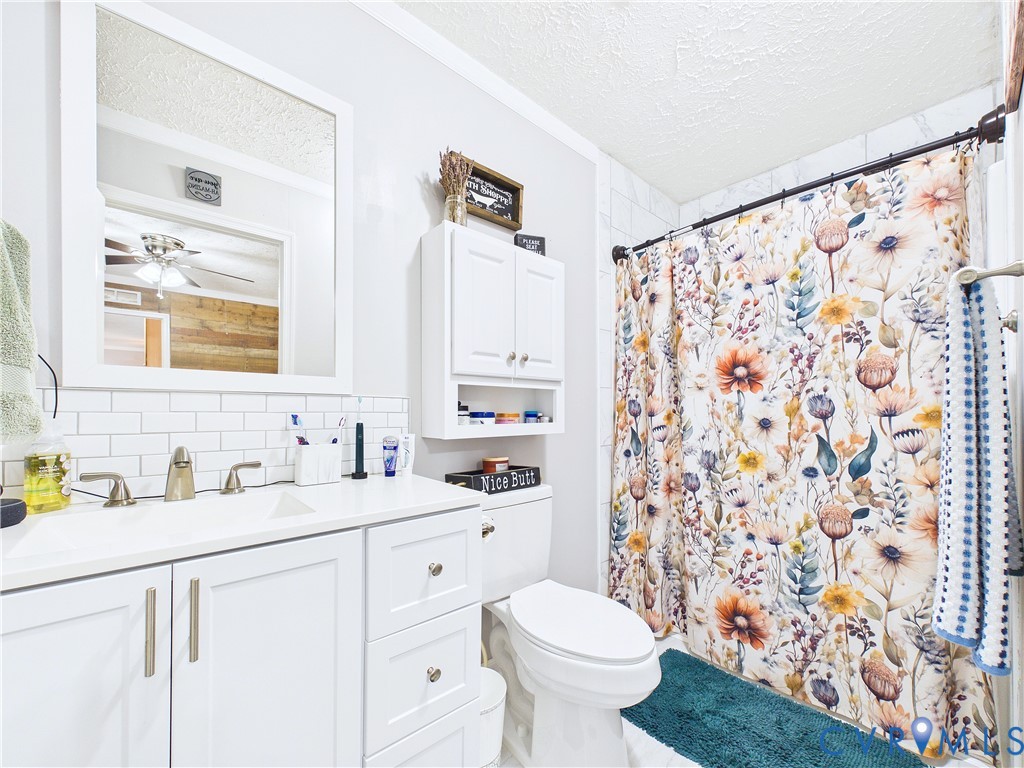 White vanity with integrated basin and undermount sink, white subway tile backsplash, wall-mounted medicine cabinet with integrated storage, and tub with shower surround