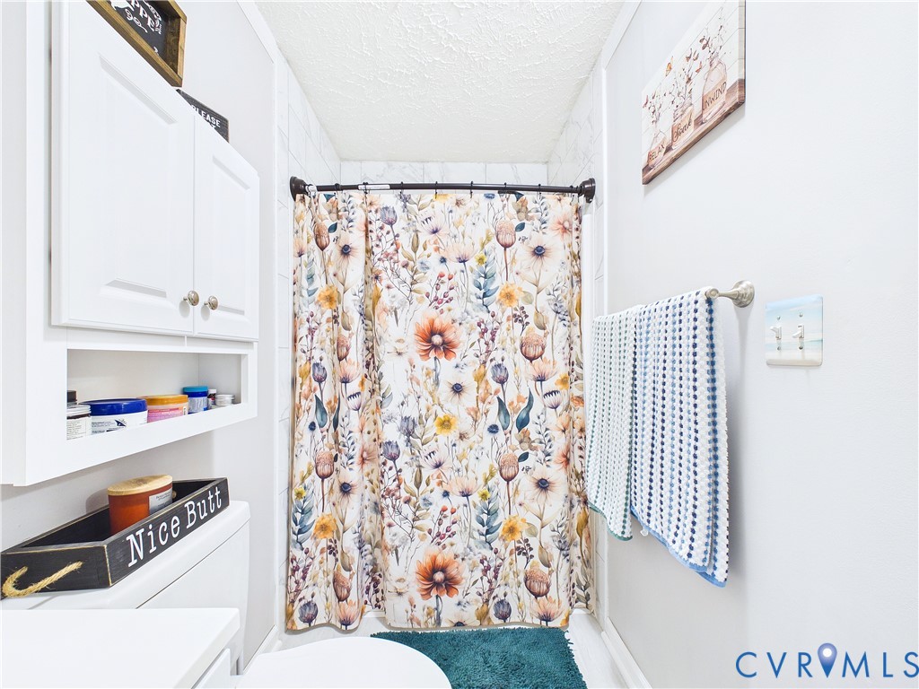 Built-in white cabinetry with open shelving and white tiled shower surround