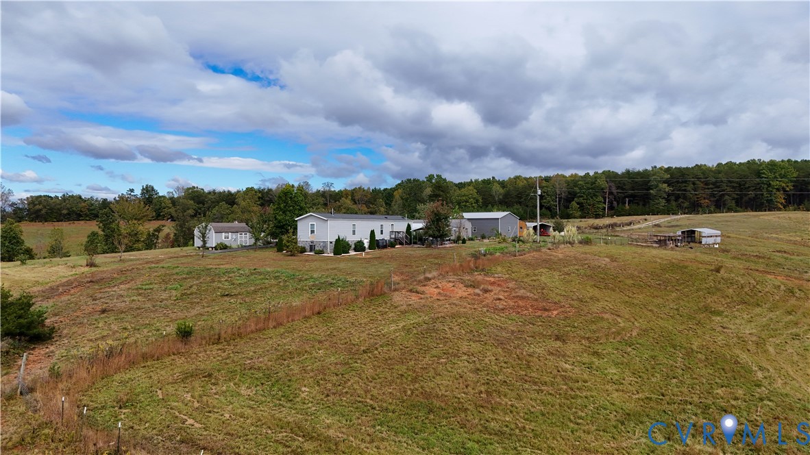 Expansive acreage featuring rolling terrain, open pasture, mature tree lines, and multiple outbuildings