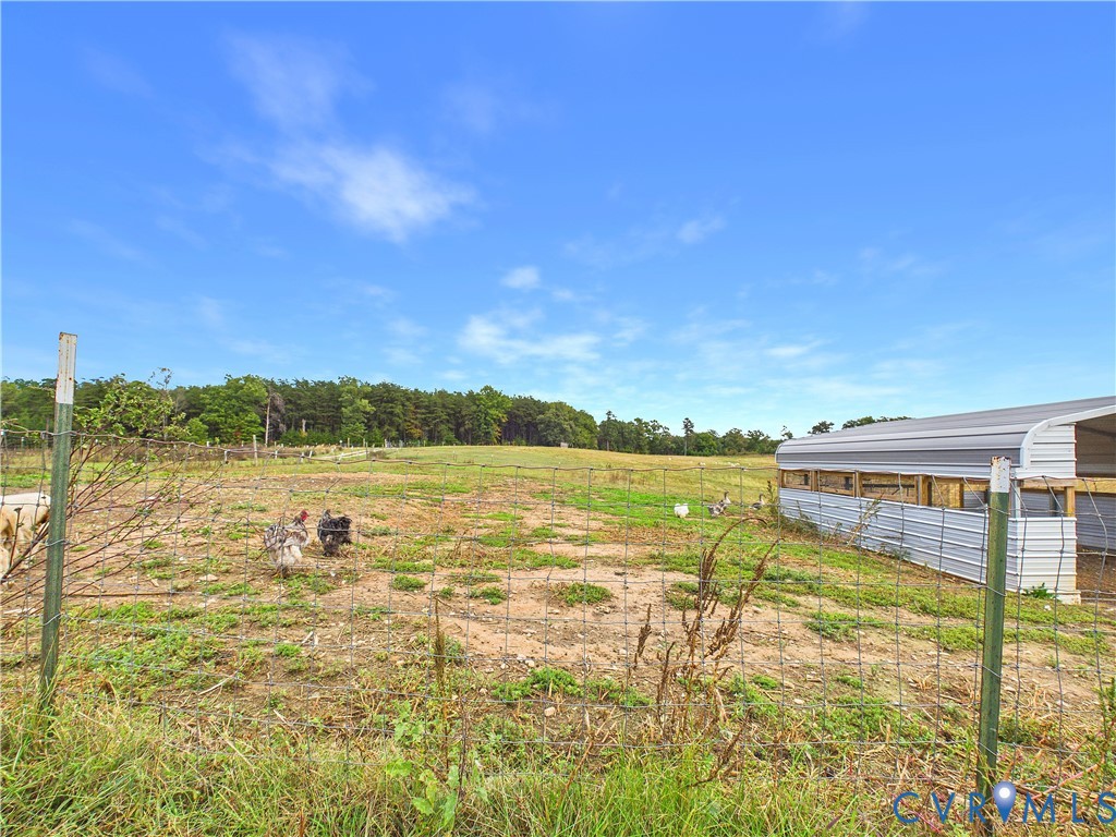 Open acreage featuring a wire perimeter fence and a metal-sided utility structure