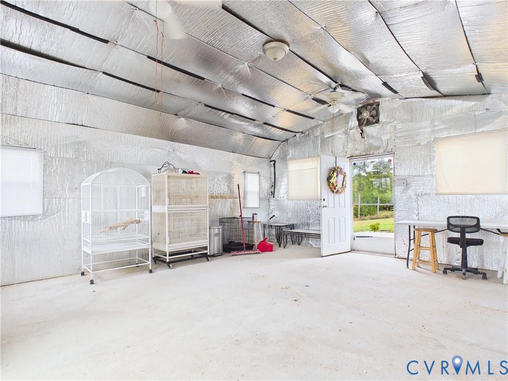 Multi-purpose structure featuring a metallic insulated ceiling and wall finish, concrete flooring, dual ceiling fans, multiple windows, and a walk-out exterior door