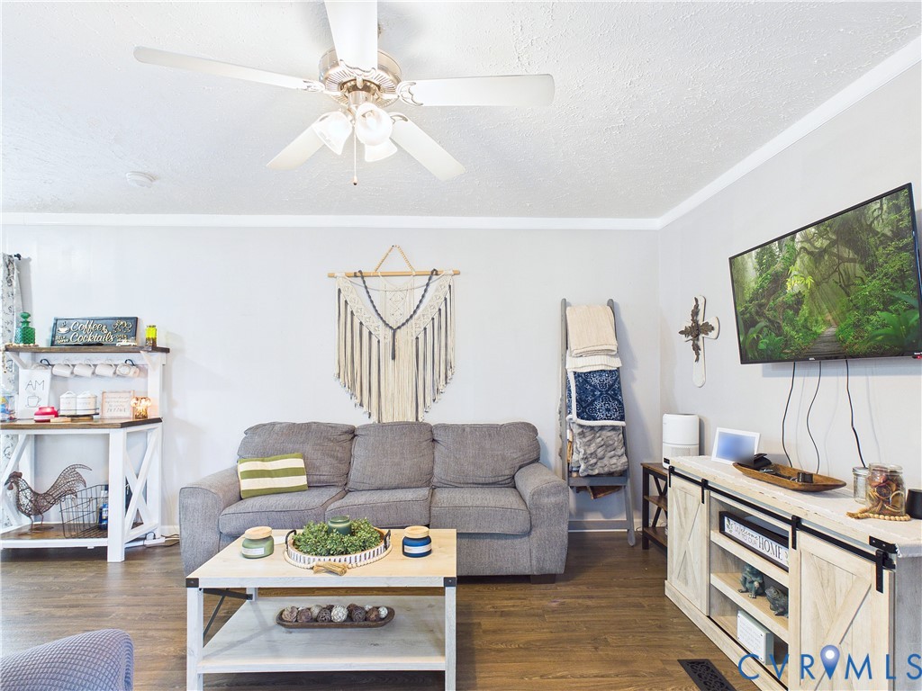 Living area featuring wood-finish flooring, white crown molding, and a central ceiling fan with integrated lighting