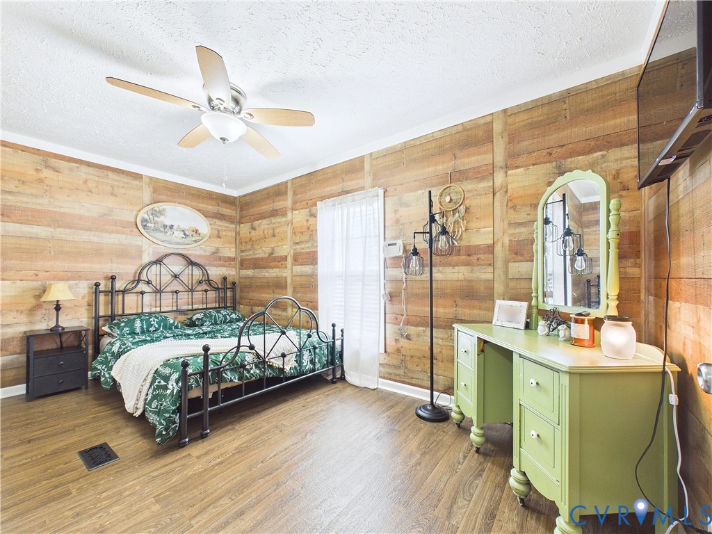 Horizontal wood plank wall paneling, wood-finish flooring, and a central ceiling fan with integrated lighting