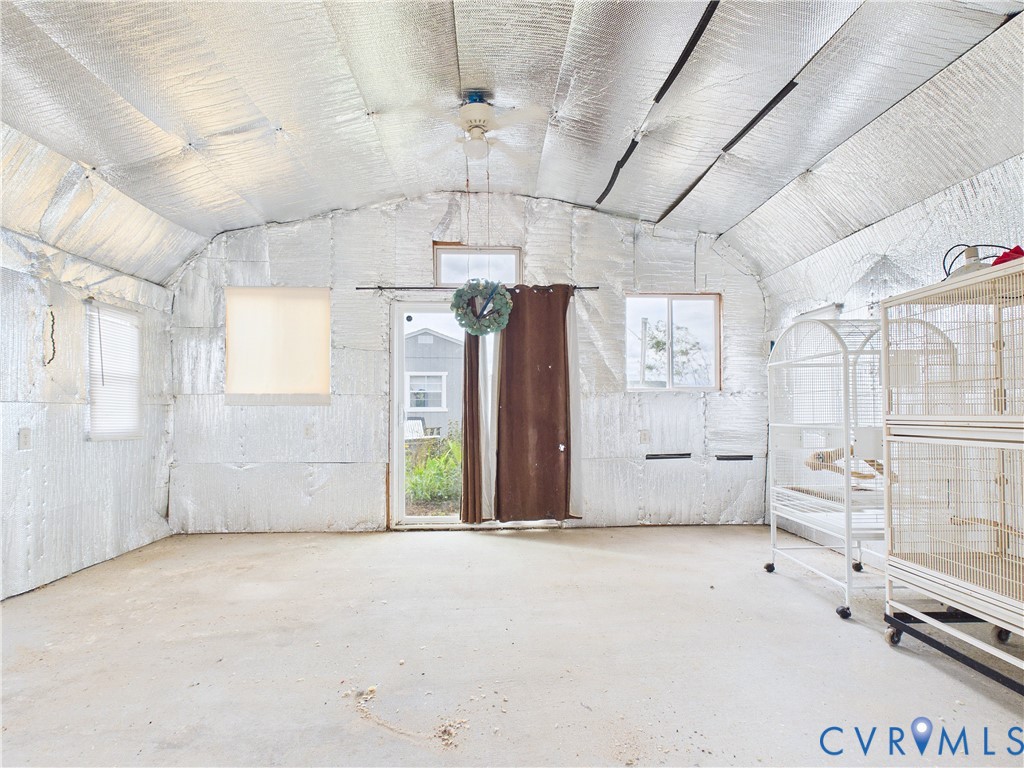 Interior space featuring reflective foil insulation, vaulted ceiling, concrete flooring, sliding glass door, and dual windows