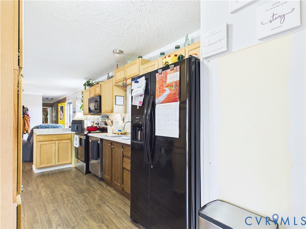 Kitchen featuring natural wood-finish cabinetry, stone-finish countertops, stainless steel appliances, and wood-finish flooring