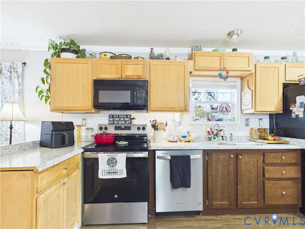 Kitchen featuring light and medium-toned cabinetry, light-colored countertops, subway tile backsplash, and stainless steel appliances Kitchen featuring light and medium-toned cabinetry, light-colored countertops, subway tile backsplash, and stainless steel appliances