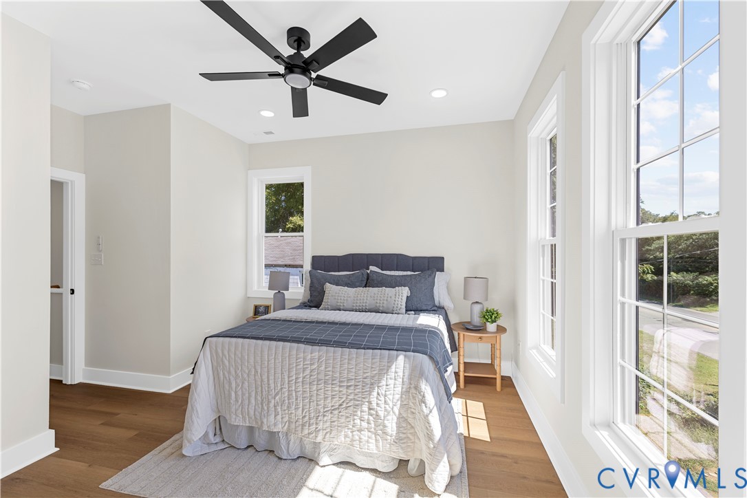 Neutral-toned interior featuring wood-finish flooring, multi-pane windows, recessed lighting, and a modern matte black ceiling fan