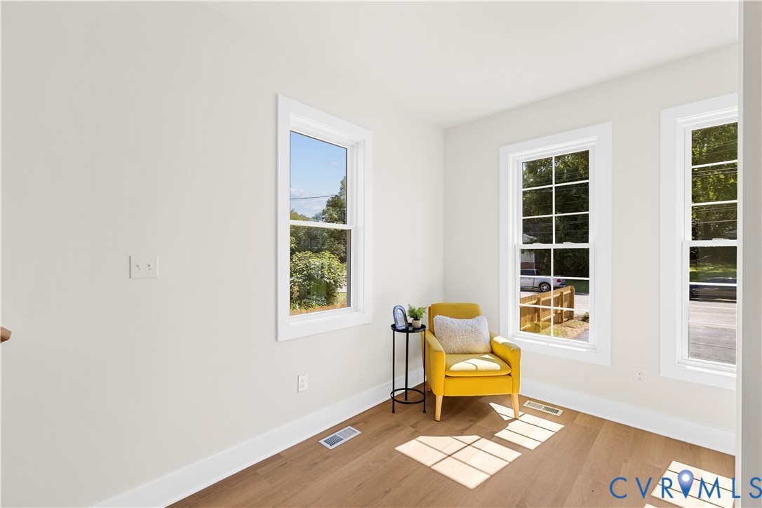 Neutral-toned interior featuring wood-finish flooring and multiple double-hung windows with grid detailing