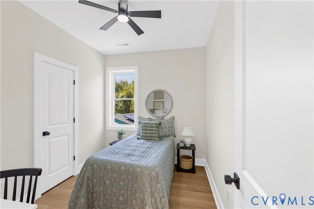 Room featuring wood-finish flooring, a matte black ceiling fan, solid-core interior doors with matte black hardware, and an energy-efficient window