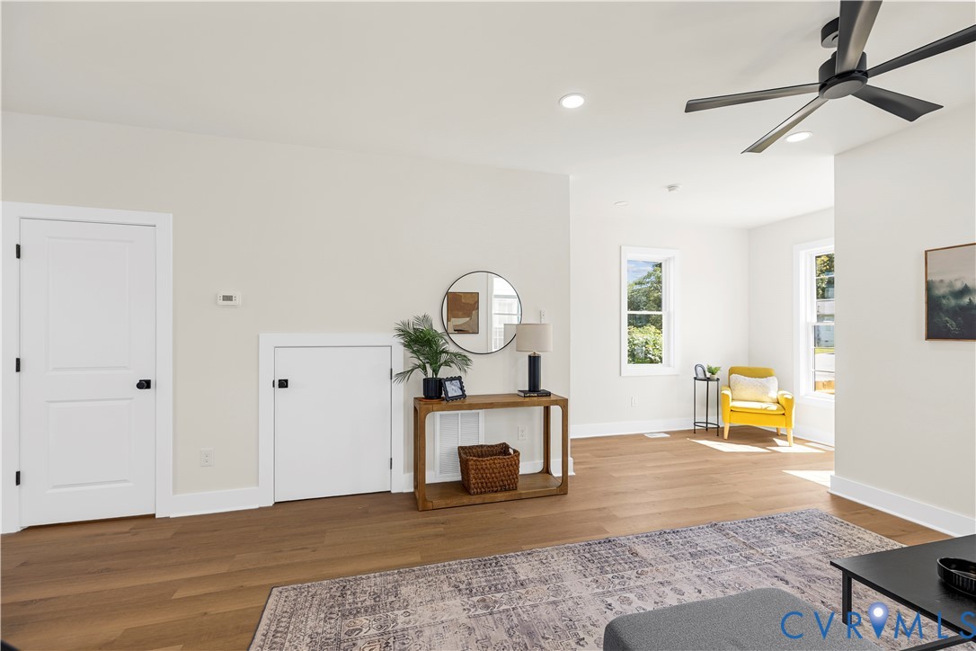 Wood-finish flooring, recessed lighting, matte black ceiling fan, and multi-pane windows