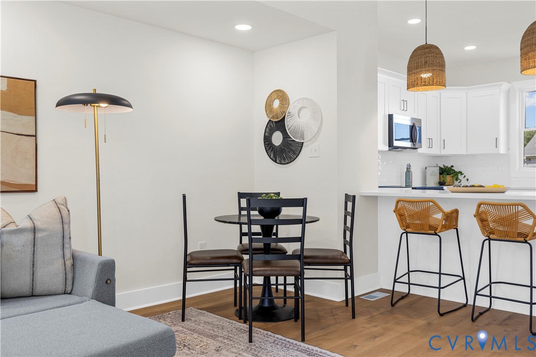 Kitchen featuring white cabinetry, a breakfast bar, recessed lighting, and wood-finish flooring Kitchen featuring white cabinetry, a breakfast bar, recessed lighting, and wood-finish flooring