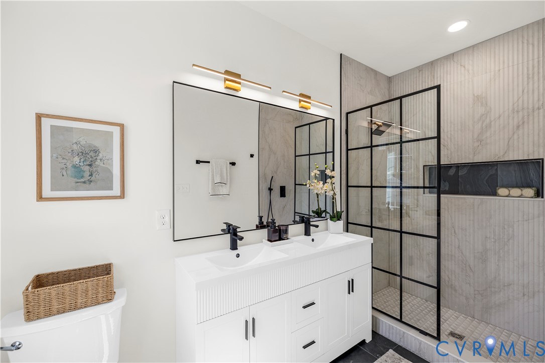White double vanity with integrated sinks, matte black hardware, large-format tiled walk-in shower with black grid enclosure, and recessed wall niche