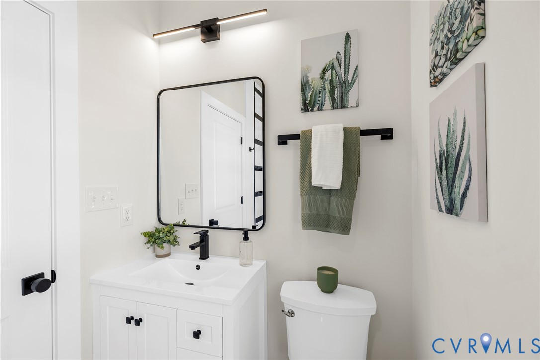 White cabinetry with integrated sink, rectangular mirror with black frame, matte black wall-mounted faucet, matching black light fixture, and coordinating black hardware