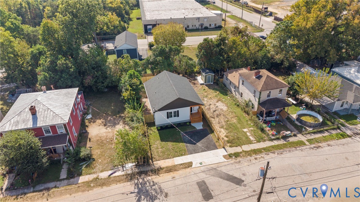 Aerial perspective featuring a detached residential structure with a shingled roof, asphalt driveway, and exterior siding