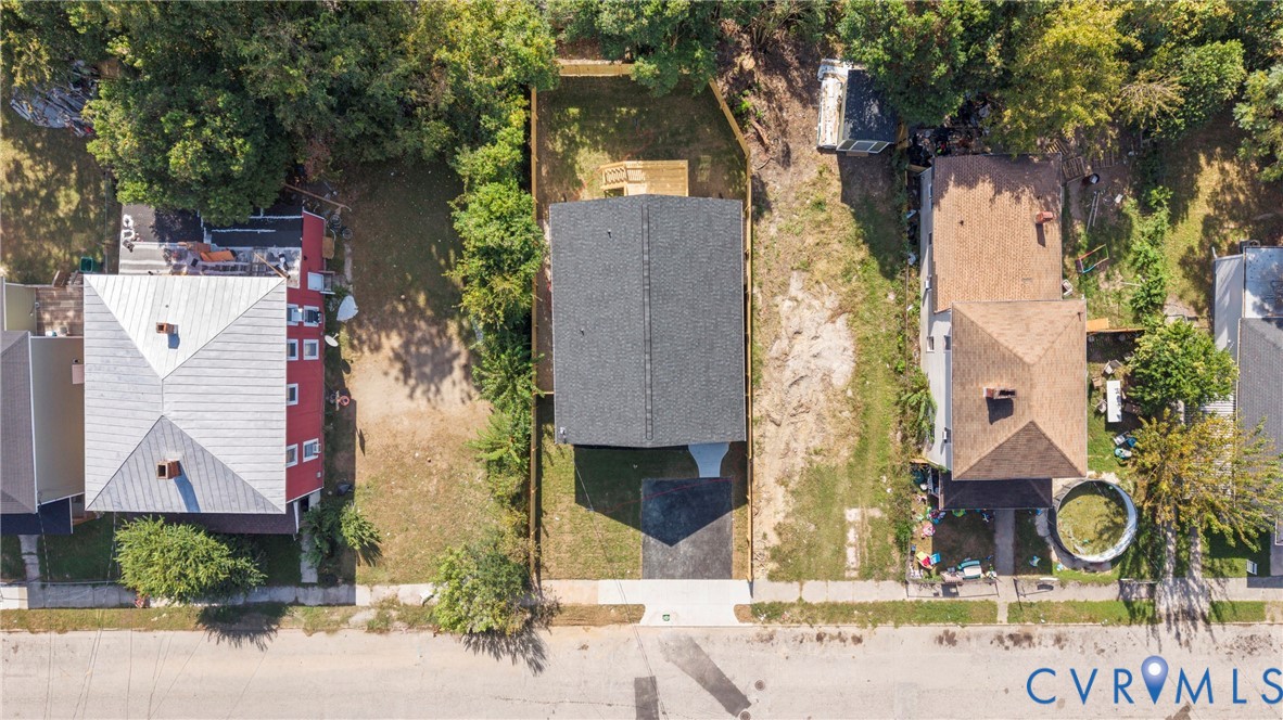 Aerial perspective of property featuring a rectangular lot, asphalt driveway, and wood-fencing enclosure