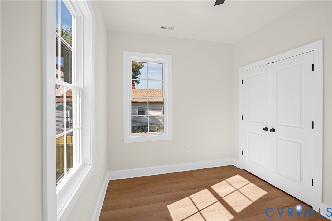 Neutral-toned interior featuring wood-finish flooring, multi-pane windows, and double doors with matte black hardware