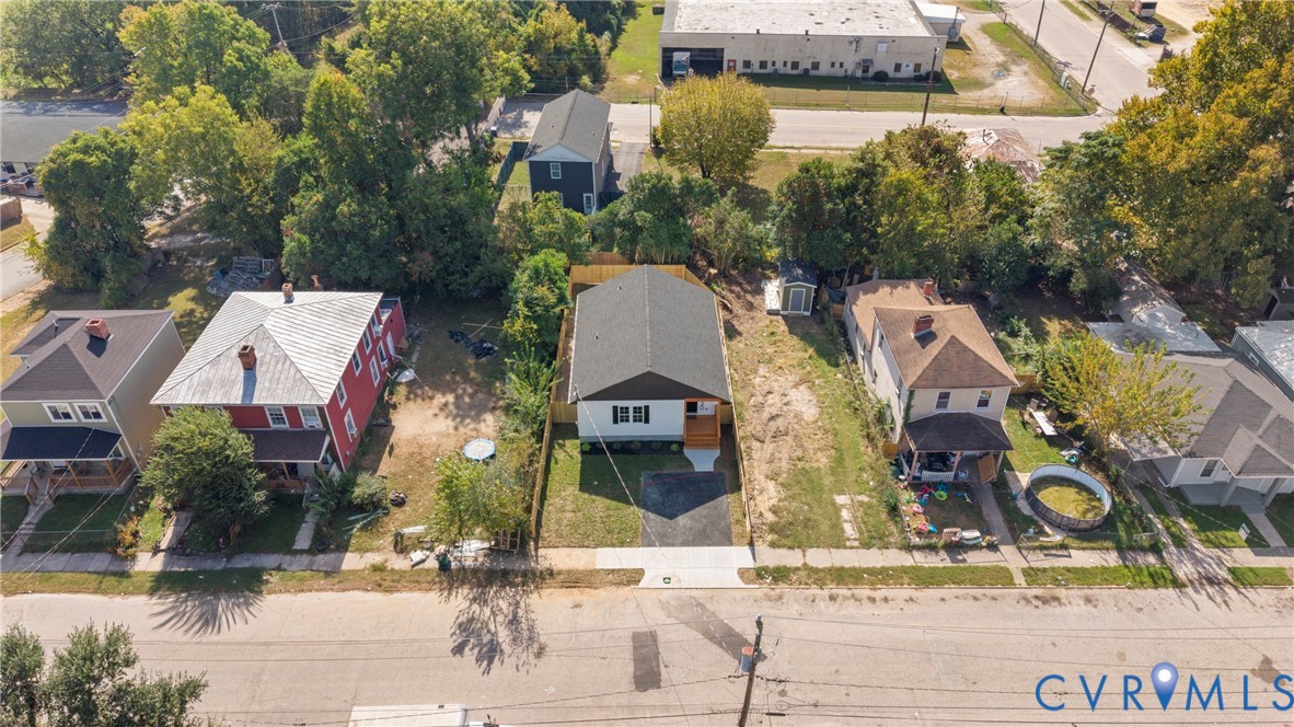 Aerial perspective featuring a detached residential structure with a shingled roof, paved driveway, and rear wooden fencing