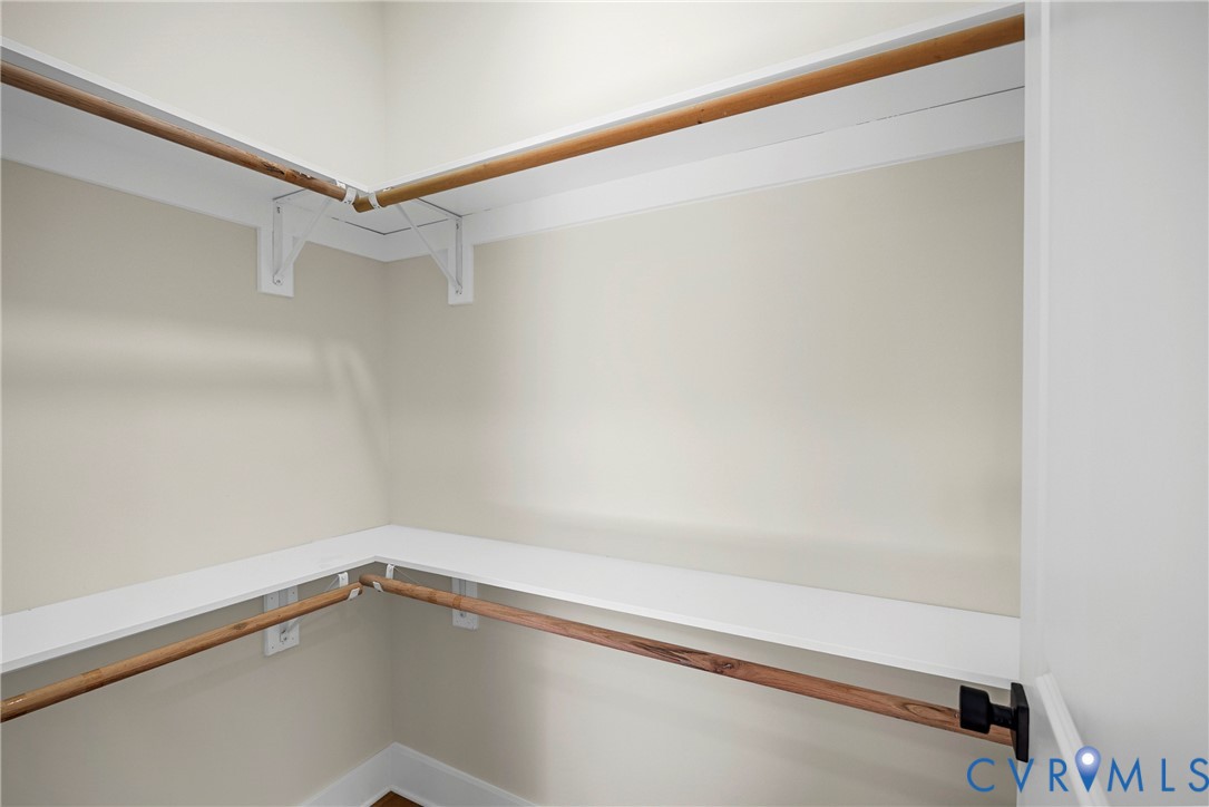 Storage area featuring dual-tier shelving and wooden closet rods
