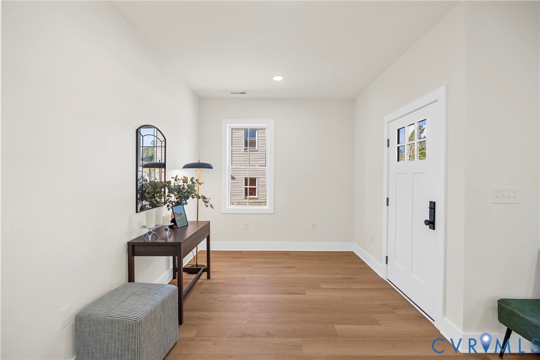 Entryway featuring wood-finish flooring, a white paneled door with glass inserts, matte black hardware, and recessed ceiling lighting