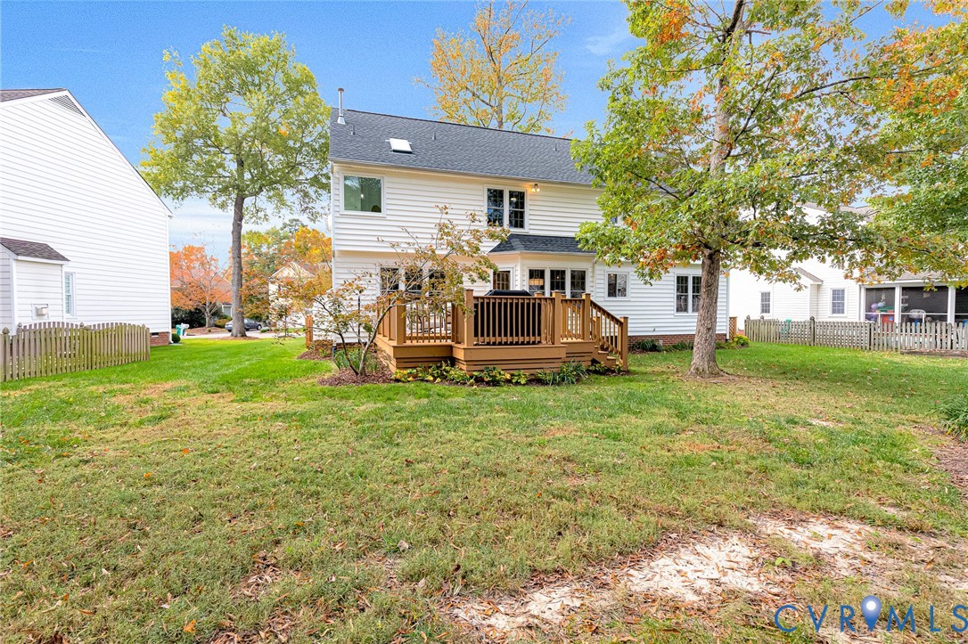 Rear exterior featuring a two-story residence with white horizontal siding, an elevated wood deck, and a fenced backyard