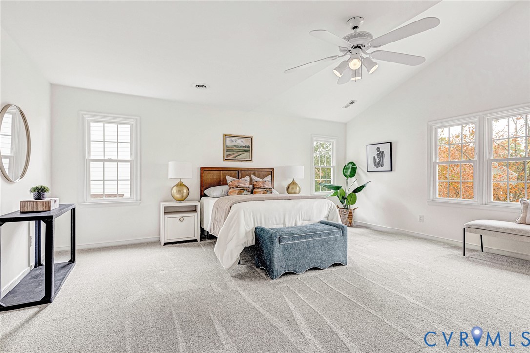 Vaulted ceiling, wall-to-wall carpeting, white-finish multi-pane windows, and a central ceiling fan with integrated lighting
