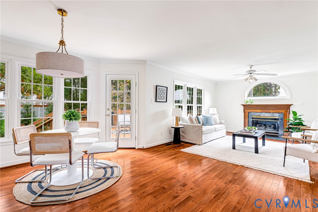 Hardwood flooring, wood-mantled fireplace with stone surround, arched transom window, glass-paneled exterior door, and pendant lighting