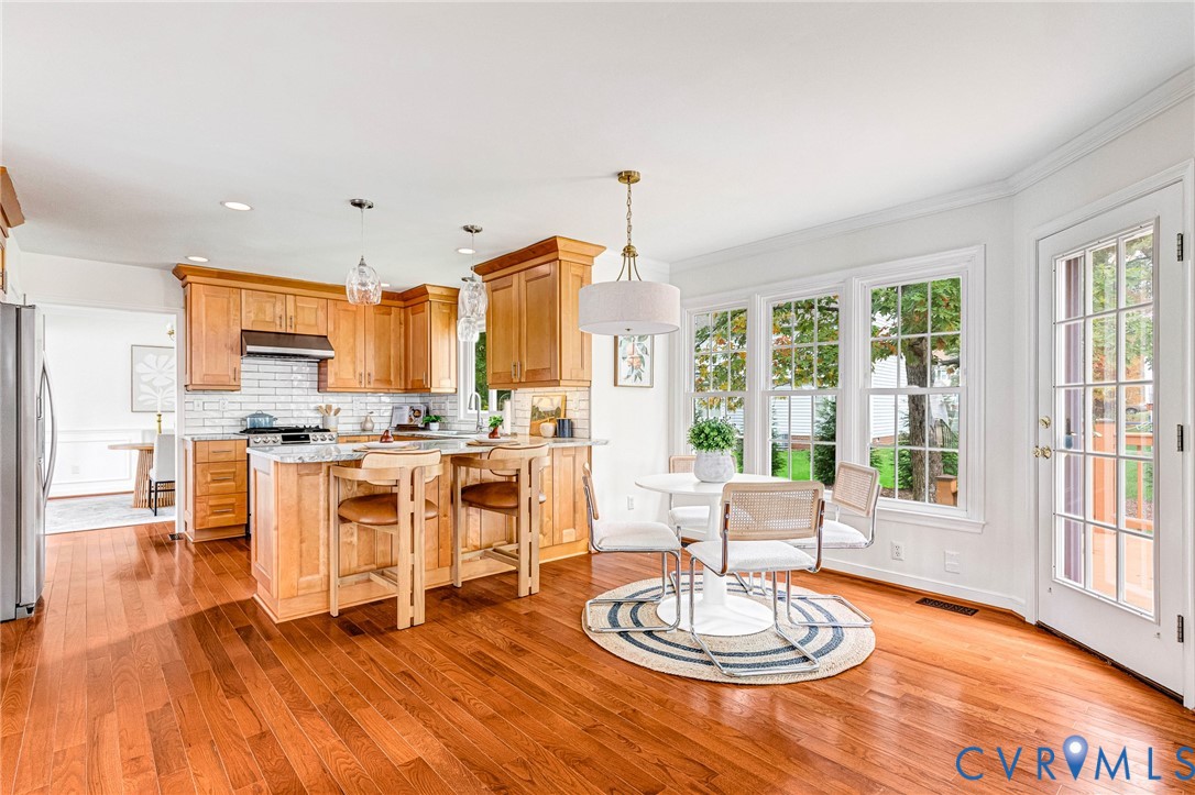 Kitchen featuring wood cabinetry, stone countertops, a subway tile backsplash, wood-finish flooring, and a glass-paneled exterior door