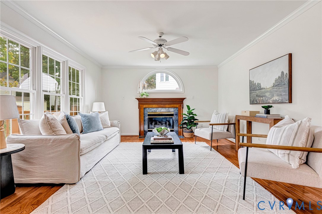 Hardwood flooring, multi-pane windows, arched window feature, and fireplace with decorative mantel and surround